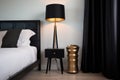 a sleek black standing lamp next to a low profile bed