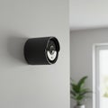 A sleek black surveillance camera is mounted on a light-colored wall. It has a cylindrical Royalty Free Stock Photo