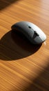 A sleek black wireless computer mouse rests on a wooden surface. The mouse Royalty Free Stock Photo