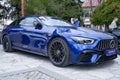 Blue Mercedes car parked on paved parking lot next to trees