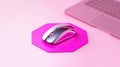 A sleek chrome wireless mouse on a vibrant pink octagonal mouse pad. Modern minimalist workspace with a laptop and copy space for Royalty Free Stock Photo