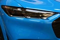Sleek headlight of modern electric compact crosover SUV car Ford Mustang Mach-E in light blue color
