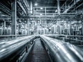 Industrial plant interior with shiny metal pipes and stainless steel tanks creating a complex network under bright ceiling lights Royalty Free Stock Photo