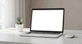A sleek laptop with a blank white screen is placed on a light-colored desk. To the left Royalty Free Stock Photo