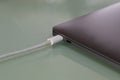 A sleek laptop is connected to a power source via a white charging cable Royalty Free Stock Photo