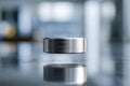 A sleek metallic cylindrical object levitating above a reflective surface with a blurred modern interior background showcasing Royalty Free Stock Photo