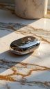 Sleek metallic object on marble surface in sunlight Royalty Free Stock Photo