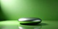 Sleek metallic object on a vibrant green surface, illuminated by a soft light source, creating a minimalist and modern aesthetic. Royalty Free Stock Photo