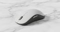 A sleek modern computer mouse with an ergonomic design sits on a white Royalty Free Stock Photo