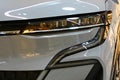 Sleek narrow headlights and S shaped stylish front day light of modern electric small family car Renault Megane E-Tech
