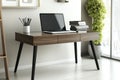 Sleek office desk featuring a laptop, a neat stack of books, and minimalistic decor. The bright space highlights the Royalty Free Stock Photo