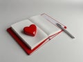 Openning note book white blank page with pen and lovely red ceramic heart shape on white background