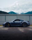 Sleek Porsche 911 car parked near the wall with majestic mountain peaks looming in the background