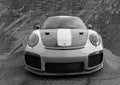 Sleek Porsche sports car parked in a gravel lot surrounded by large rocky formations