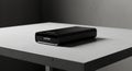 A sleek, rectangular black device, resembling a portable hard drive, rests on a gray, Royalty Free Stock Photo