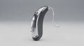 Modern Hearing Aid Device Silver with Earbud on Gray Background Royalty Free Stock Photo