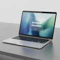 A sleek silver laptop is positioned on a gray table. The screen displays a login Royalty Free Stock Photo
