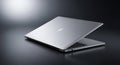Sleek silver laptop resting on a dark reflective surface with dramatic lighting Royalty Free Stock Photo