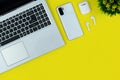 Modern Tech Workspace With Laptop, Smartphone, AirPods And Plant On Bright Yellow Background.Ideal for tech, work, and lifestyle t Royalty Free Stock Photo