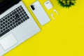 Modern Tech Workspace With Laptop, Smartphone, AirPods And Plant On Bright Yellow Background.Ideal for tech, work, and lifestyle t Royalty Free Stock Photo