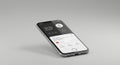 A sleek smartphone lies on a light gray surface, slightly angled. It features a dark
