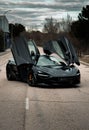 Sleek and stylish McLaren sports car sits on a roadway with the doors up