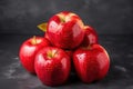 A pile of red apples with leaves on table, black background