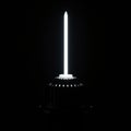 A sleek, vertical light source projects from a dark, metallic base. The light is bright Royalty Free Stock Photo