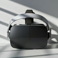 A sleek virtual reality headset with a black front and metallic gray frame rests on a white