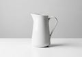 A sleek, white ceramic pitcher is positioned on a smooth, white surface. The pitcher has a curved Royalty Free Stock Photo