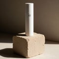 A sleek white cylindrical object stands upright on a textured beige block Royalty Free Stock Photo