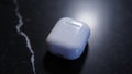 White wireless earbuds case placed on dark marble surface with soft reflection Royalty Free Stock Photo