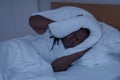 Sleep Disorders. Black Man Lying In Bed And Covering Head With Pillow Royalty Free Stock Photo