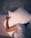 Sleep, insomnia and woman with pillow on head, tired and frustrated with stress, nightmare or dream in bedroom. Fatigue