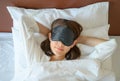 High angle view of young beautiful woman wearing sleep mask during sleeping on the bed.