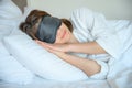 Portrait of young beautiful woman wearing sleep mask during sleeping on the bed.