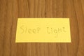 Sleep tight handwrite on a yellow paper with a pen on a table