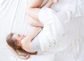 Sleep. Young woman sleeping in bed, female resting on comfortable bed with pillows in white bedding in light bedroom in morni Royalty Free Stock Photo