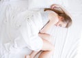 Sleep. Young woman sleeping in bed, female resting on comfortable bed with pillows in white bedding in light bedroom Royalty Free Stock Photo