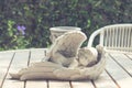 Sleeping angel cupid statue on wooden table and chair in the garden, vintage photo Royalty Free Stock Photo