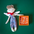 Sleeping angel toy and orange alarm clock on a dark green background. Royalty Free Stock Photo