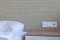 Sleeping area, bedroom in resort hotel with bed, bedside table, group of socket and switches on a wall Royalty Free Stock Photo
