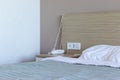 Sleeping area, bedroom in resort hotel with bed, bedside table, group of sockets and switch, telephone for contacting the Royalty Free Stock Photo