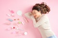 Sleeping Asian woman lying on pink background with her cosmetics. Top view Royalty Free Stock Photo