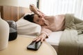 Sleeping asian woman turning off alarm on smartphone while being Waken up in the morning Royalty Free Stock Photo