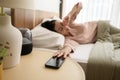 Sleeping asian woman turning off alarm on smartphone while being Waken up in the morning Royalty Free Stock Photo