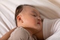 Sleeping baby boy is snuggling with mom is the most warmest moment. An innocent Asian kid is chubby, cute in grey pajamas laying