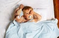 Baby boy waking up in the bed with toy, wipe eyes Royalty Free Stock Photo