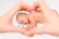 A sleeping baby with his favorite knitted toy. Selective focus on the child through the hands of the mother making a heart-shaped Royalty Free Stock Photo