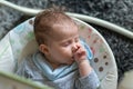 Sleeping baby in swing automatic electrical chair and sucking left thumb Royalty Free Stock Photo